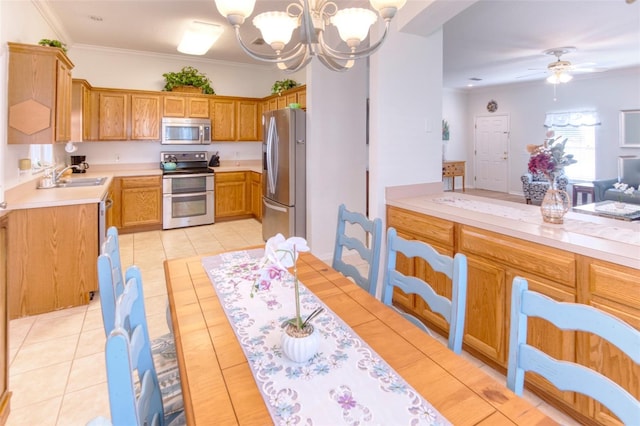 kitchen with appliances with stainless steel finishes, ornamental molding, sink, light tile patterned floors, and hanging light fixtures