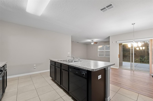 kitchen with ceiling fan with notable chandelier, sink, light tile patterned floors, black dishwasher, and an island with sink