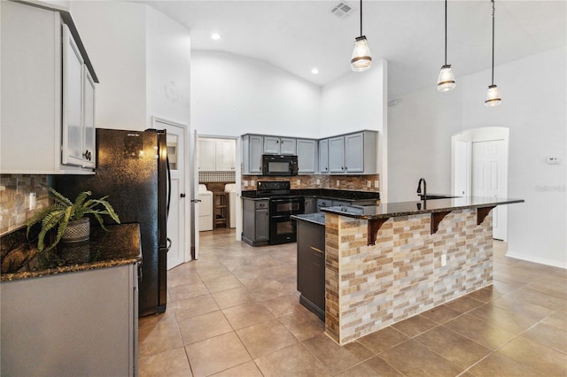 kitchen featuring light tile patterned flooring, a towering ceiling, decorative light fixtures, a center island, and black appliances