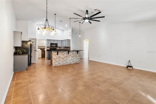 kitchen with a breakfast bar, high vaulted ceiling, pendant lighting, decorative backsplash, and black appliances