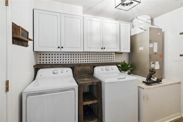 laundry area featuring separate washer and dryer, heating unit, cabinets, and a textured ceiling