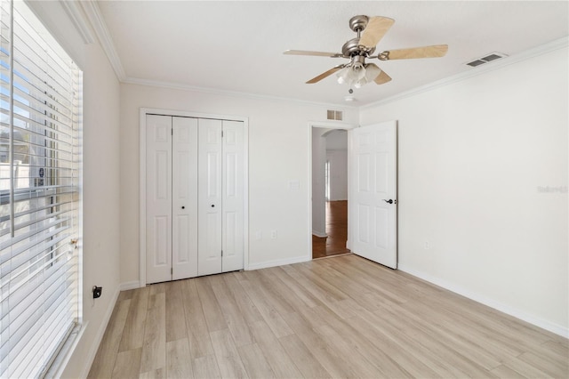 unfurnished bedroom featuring crown molding, light hardwood / wood-style floors, ceiling fan, and a closet