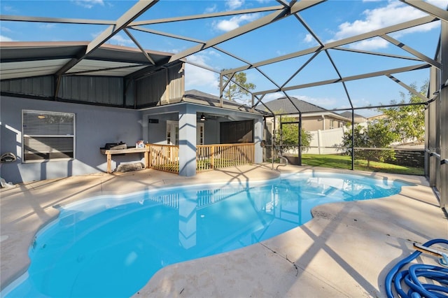 view of pool with a patio area, ceiling fan, and glass enclosure