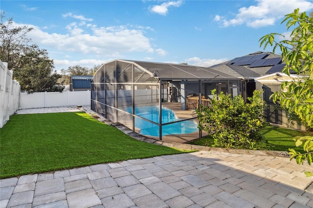 view of swimming pool featuring glass enclosure, a patio area, and a lawn