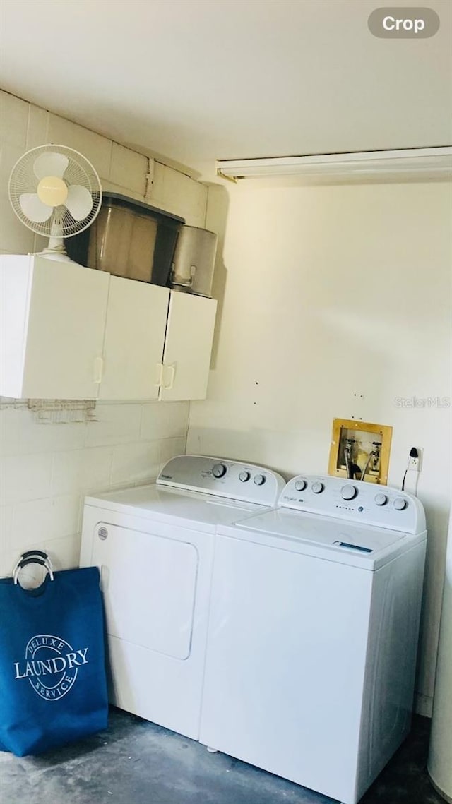 laundry area featuring washing machine and clothes dryer and cabinets