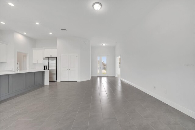 unfurnished living room featuring light tile patterned floors, a towering ceiling, and sink