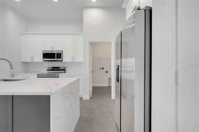 kitchen featuring sink, light stone countertops, white cabinetry, and stainless steel appliances