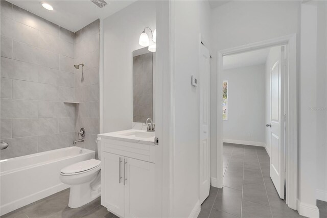 full bathroom featuring tile patterned flooring, vanity, toilet, and tiled shower / bath combo