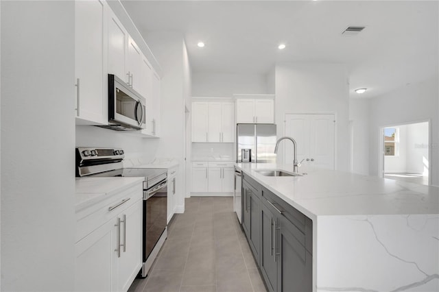 kitchen featuring white cabinets, sink, stainless steel appliances, and an island with sink