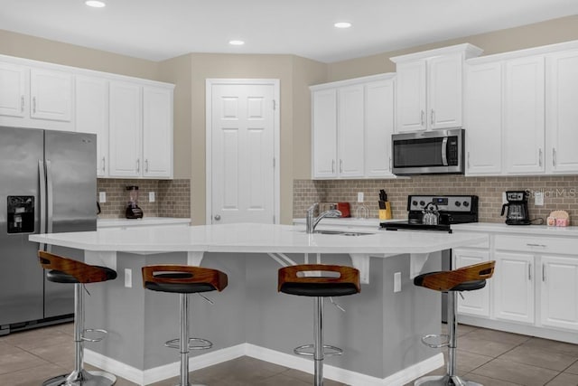 kitchen with white cabinets, stainless steel appliances, and a center island with sink