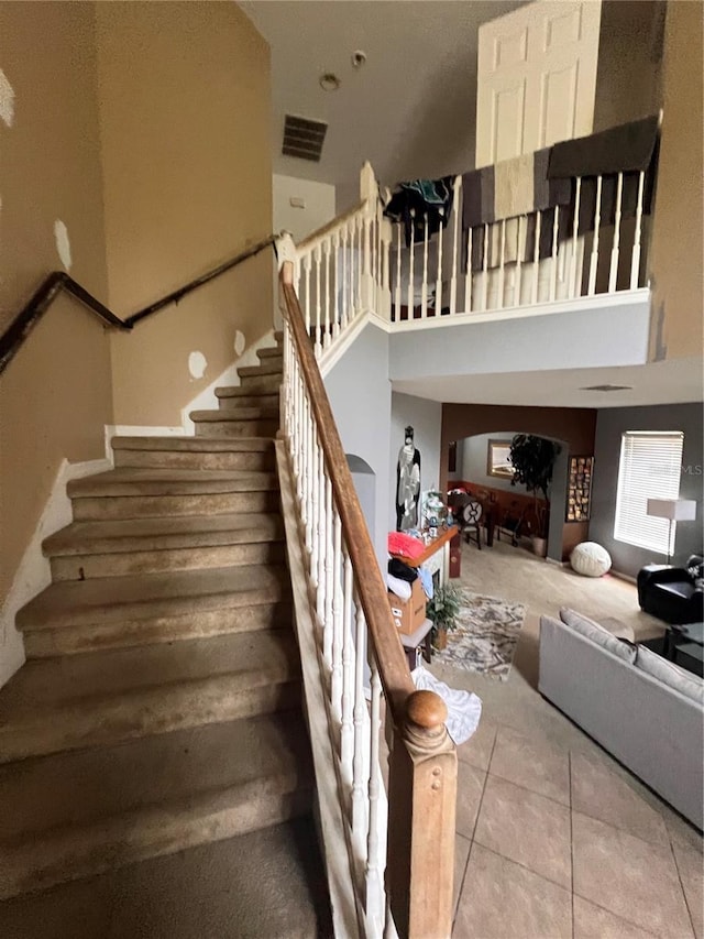 stairs featuring tile patterned flooring and a towering ceiling