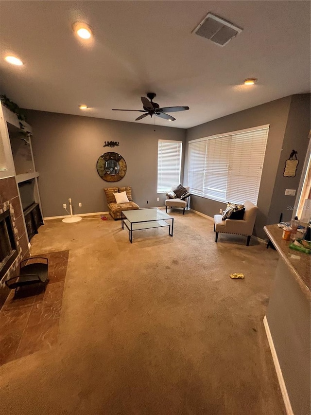 living area featuring a fireplace, carpet floors, and ceiling fan