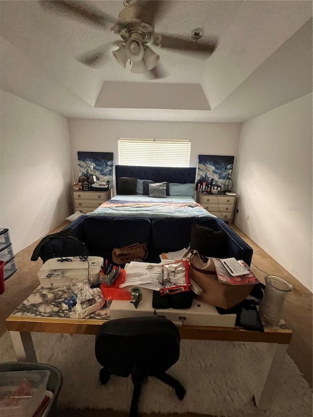 bedroom with a textured ceiling, a raised ceiling, and ceiling fan