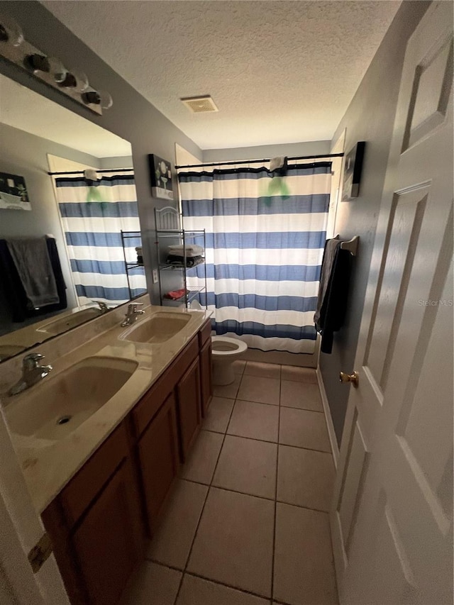 bathroom featuring tile patterned floors, walk in shower, vanity, a textured ceiling, and toilet