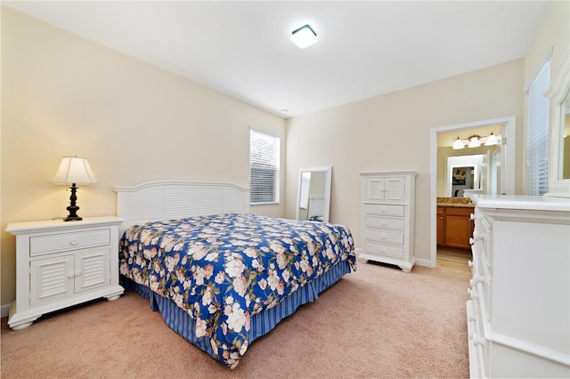 bedroom featuring ensuite bathroom and light carpet