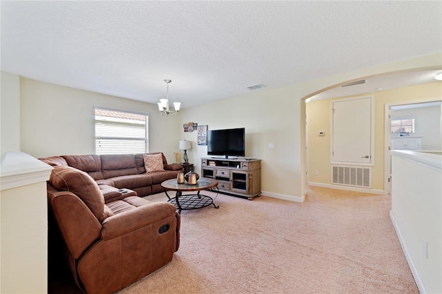 living room featuring a textured ceiling, light carpet, a wealth of natural light, and a chandelier