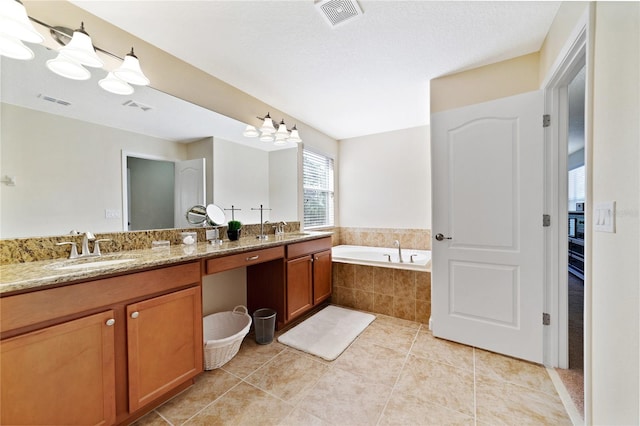 bathroom featuring tile patterned flooring, vanity, and tiled tub