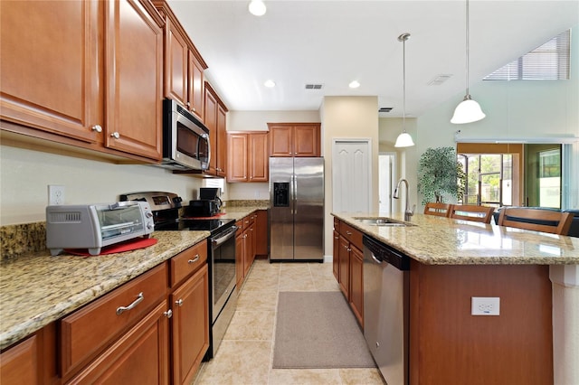 kitchen featuring a kitchen breakfast bar, sink, light stone countertops, an island with sink, and appliances with stainless steel finishes