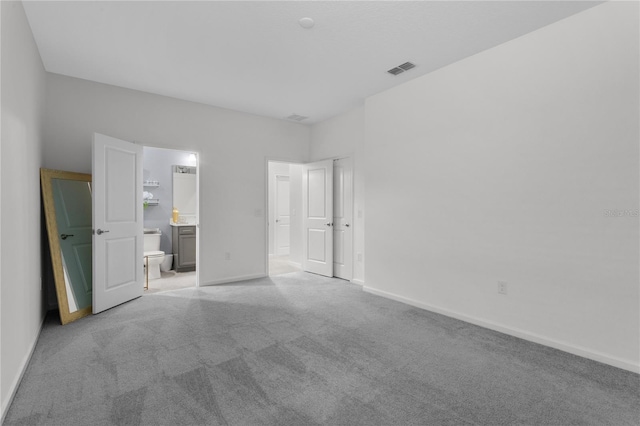 unfurnished bedroom featuring connected bathroom and light carpet