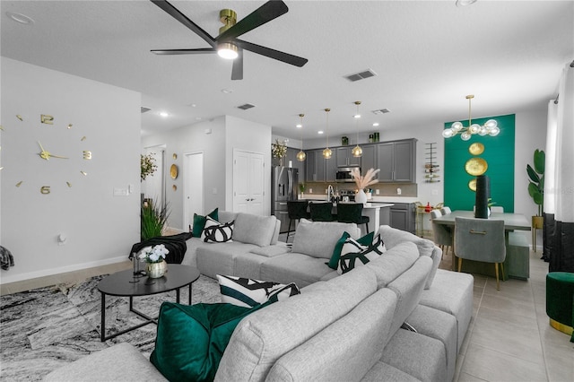 living room featuring ceiling fan with notable chandelier and a textured ceiling