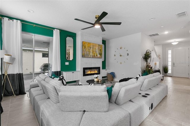 living room featuring ceiling fan, a large fireplace, and a textured ceiling