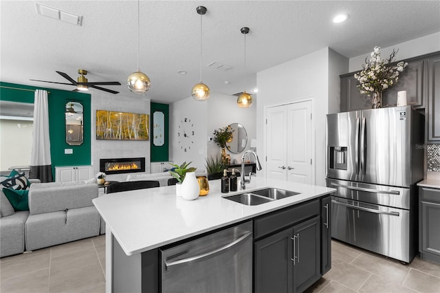 kitchen with sink, a textured ceiling, stainless steel appliances, and an island with sink