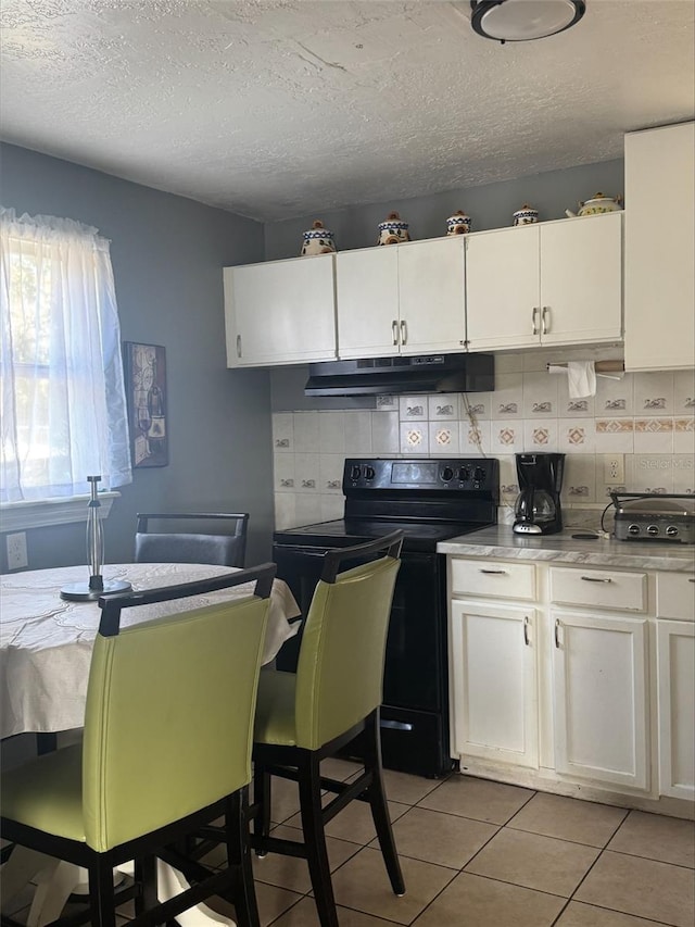 kitchen with white cabinets, light tile patterned floors, black range with electric cooktop, and backsplash