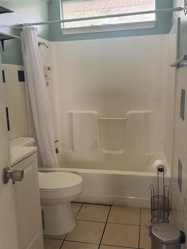 bathroom with tile patterned floors, shower / bath combo with shower curtain, and toilet