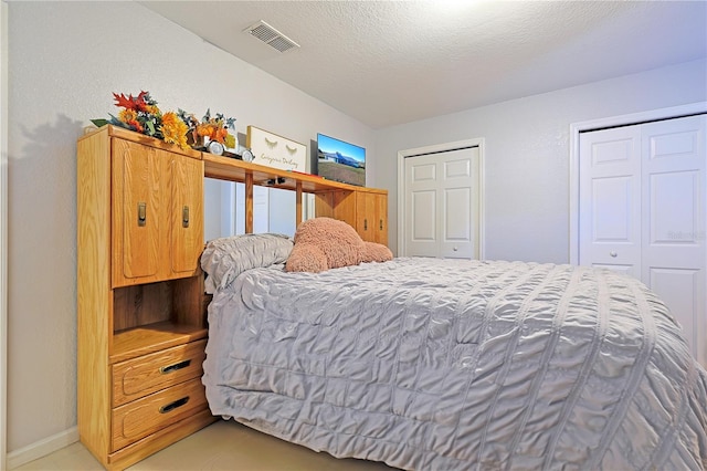 bedroom featuring multiple closets and a textured ceiling