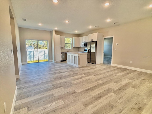 kitchen featuring backsplash, stainless steel appliances, sink, white cabinets, and a center island