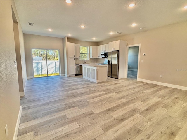 kitchen featuring sink, a kitchen island, decorative backsplash, white cabinets, and appliances with stainless steel finishes