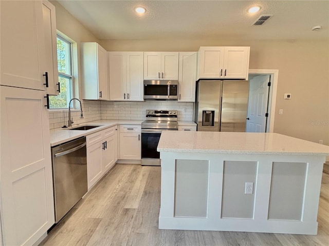 kitchen with light stone counters, sink, white cabinets, and stainless steel appliances