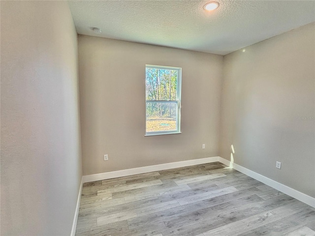 spare room with light wood-type flooring and a textured ceiling