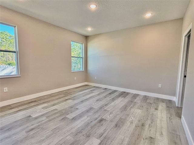 unfurnished room featuring light wood-type flooring and a textured ceiling