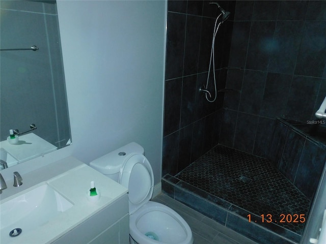 bathroom featuring tiled shower, vanity, and toilet