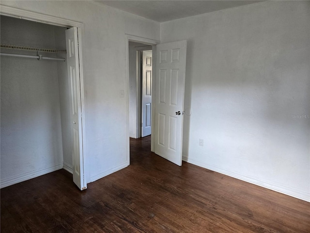 unfurnished bedroom featuring a closet and dark hardwood / wood-style floors