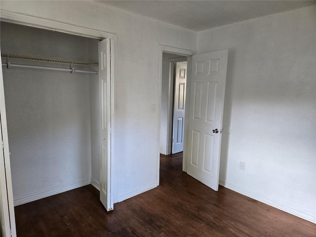 unfurnished bedroom with dark wood-type flooring and a closet