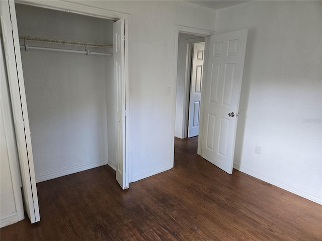 unfurnished bedroom with dark hardwood / wood-style flooring and a closet