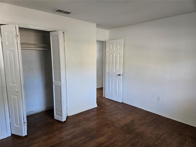 unfurnished bedroom featuring dark hardwood / wood-style flooring and a closet