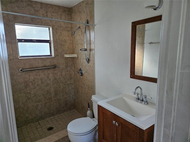 bathroom with a tile shower, vanity, and toilet