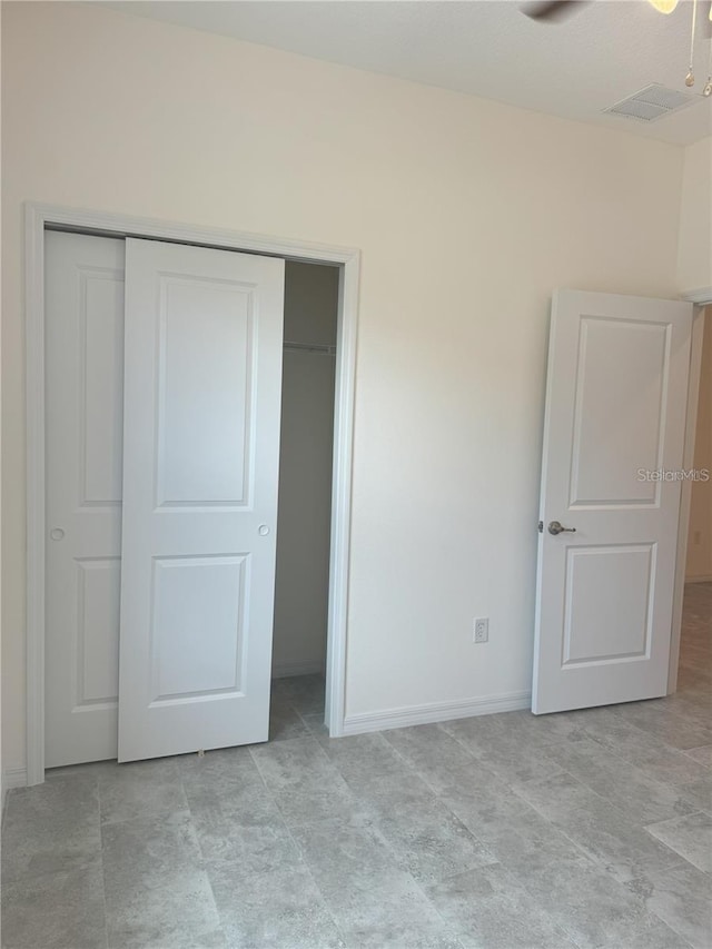 unfurnished bedroom with ceiling fan and a closet