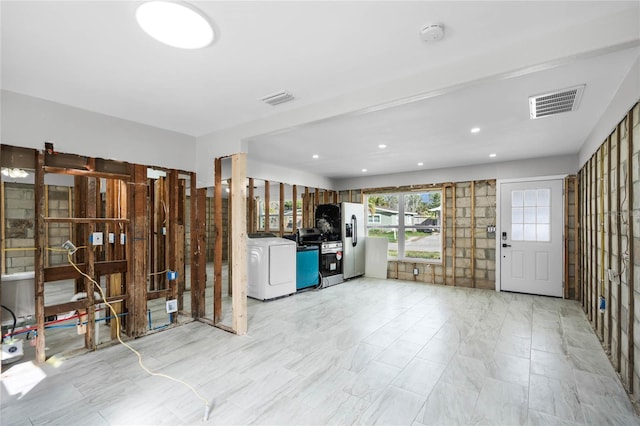 interior space featuring stainless steel fridge with ice dispenser and washer / clothes dryer