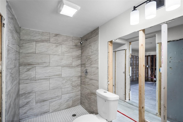 bathroom featuring tiled shower and toilet