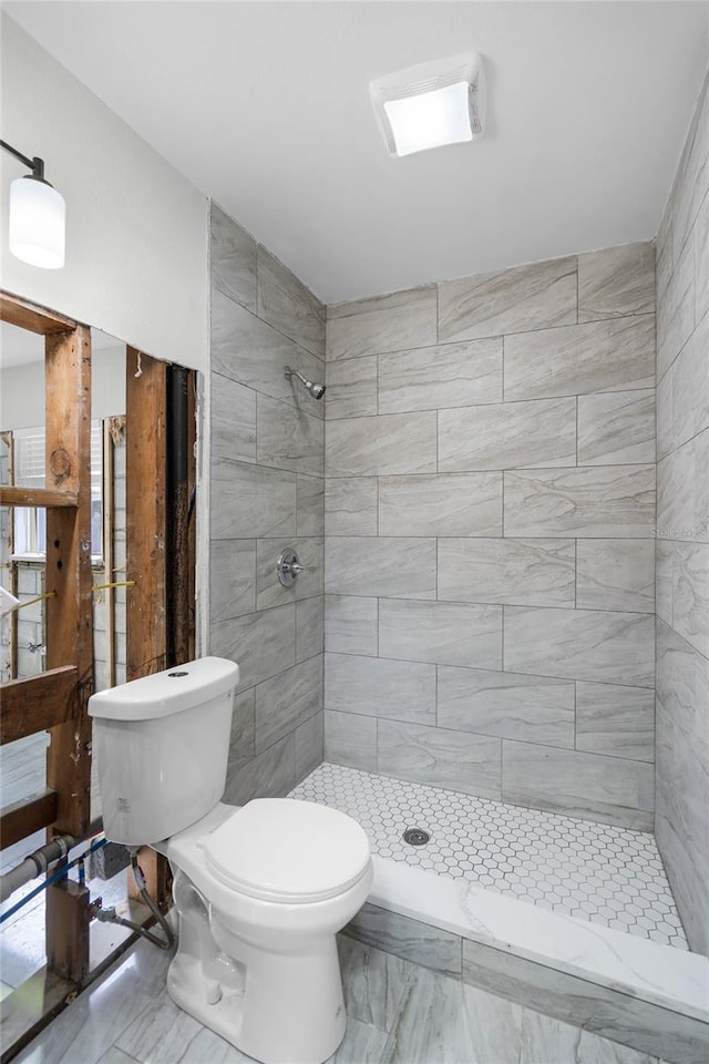 bathroom featuring toilet and a tile shower