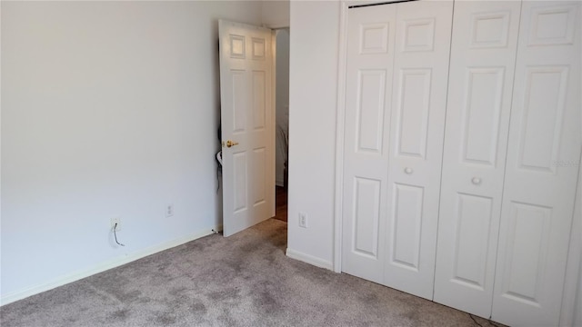 unfurnished bedroom with light colored carpet and a closet