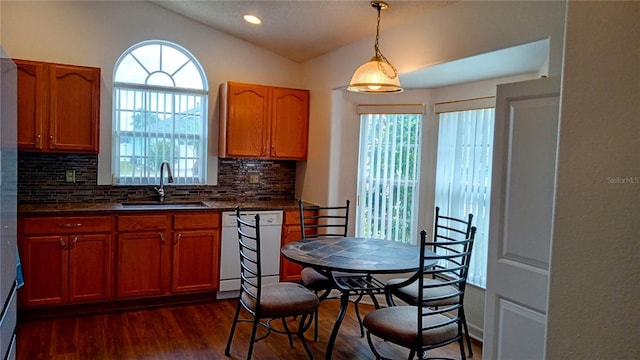 kitchen with tasteful backsplash, lofted ceiling, white dishwasher, hanging light fixtures, and sink