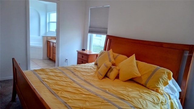 bedroom featuring ensuite bathroom, light tile patterned flooring, and multiple windows