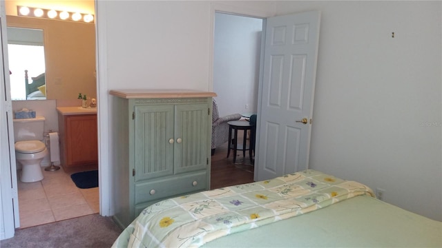 bedroom with ensuite bath and tile patterned flooring