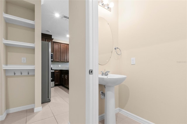 bathroom with sink, tile patterned flooring, crown molding, a textured ceiling, and decorative backsplash