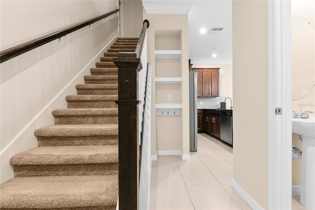 stairway featuring crown molding, tile patterned flooring, and sink